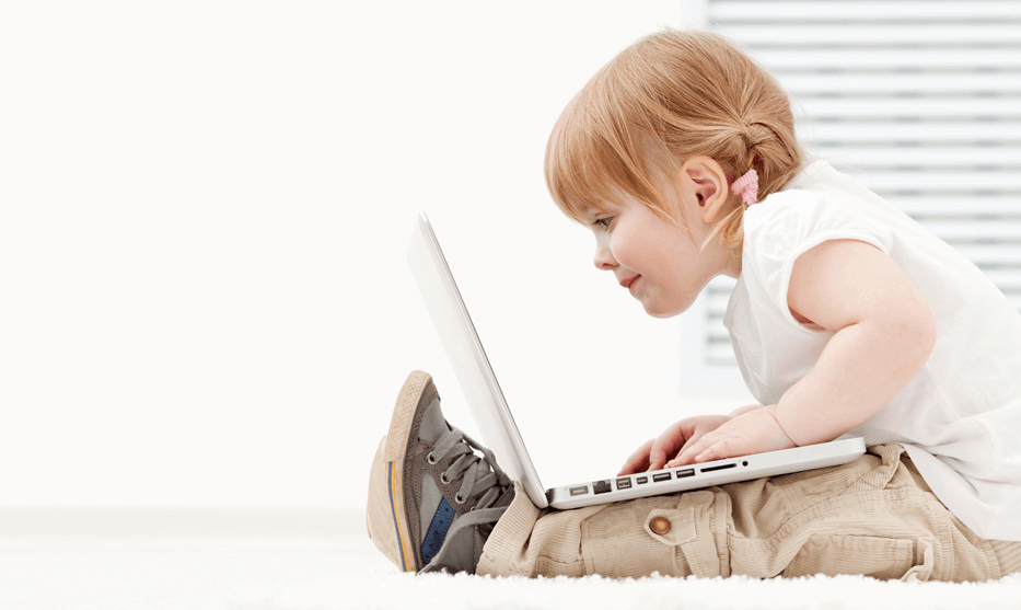 a young girl intently studies the screen of a laptop