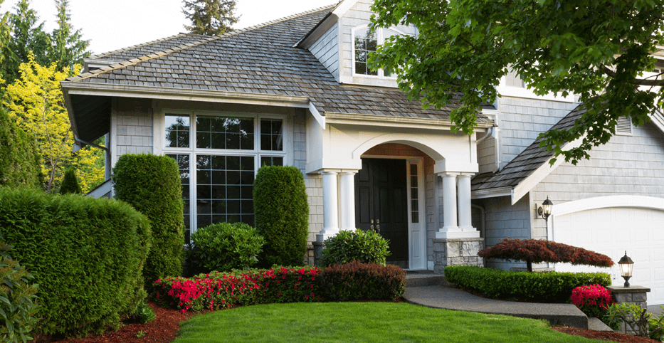 the front entrance to a traditional upscale home with pristine landscaping