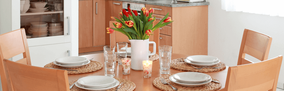 a de-cluttered kitchen table setting with a bouquet of tulips artistically displayed in a pitcher