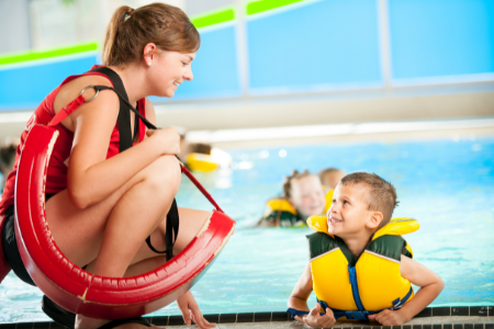 lifeguard checking on boy in safety lifejacket