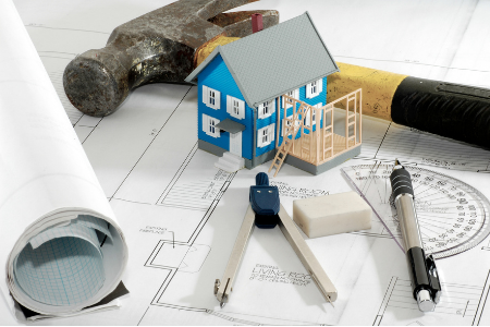 home improvement project planning with a hammer, protractor, and small house over floorplans