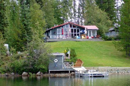 A cottage by the water with a gray dock.