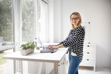A woman standing at her desk in the home office.