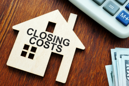 a wooden house and a calculator symbolizing closing costs