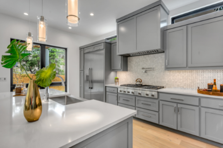 A kitchen that has been updated with new gray cabinetry and backsplash.