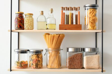 Jars and cannisters to organize food on a shelf.