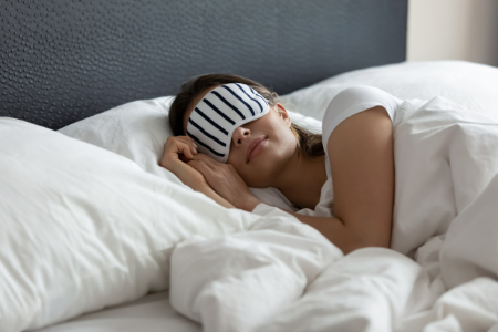 A woman sleeping with a mask to avoid insomnia in a new home.