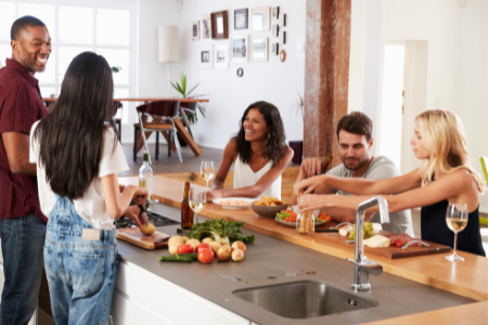 A group getting together in the kitchen, one of the most cost-effective entertaining options.