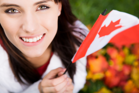 A woman with a Canadian flag in her hand, symbolizing moving to Canada.