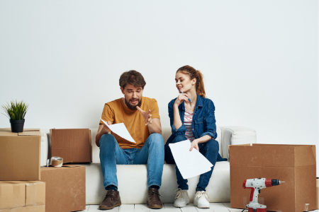 A man with buyer's remorse talking to his friend among moving boxes.
