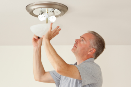 A man swapping out incandescent bulbs for LED options.