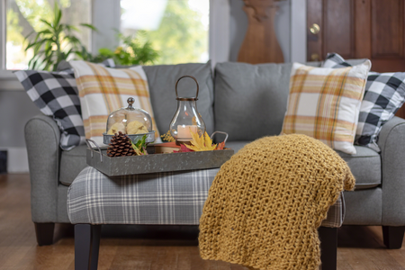 A gray couch with a chunky knit blanket and plaid pillows.