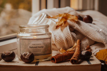 A scented candle with cloves and leaves nearby.