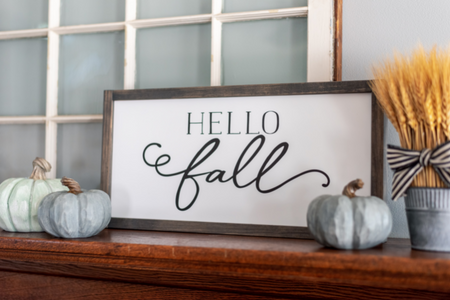 A sign reading "hello fall" on a mantel.