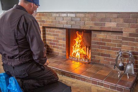 A man inspecting a fireplace before the winter season.