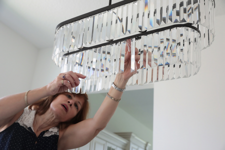 A woman installing a new light fixture in the dining room.