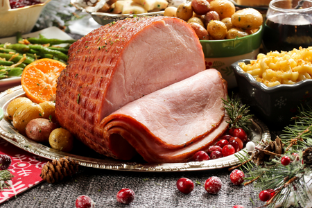A carved ham sitting on a table during the holidays.
