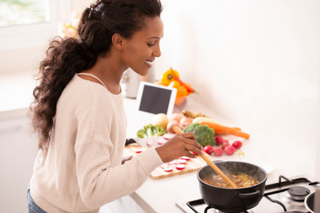 A woman trying a winter weather recipe by cooking soup on the stovetop.