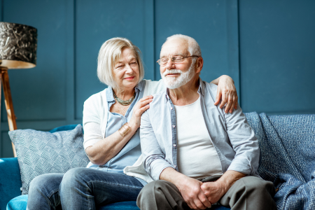 Two seniors sitting on a couch happily, symbolizing home safety of seniors.