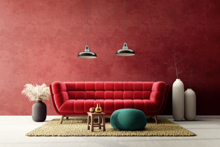 A velvet red couch in front of a dusty red wall.