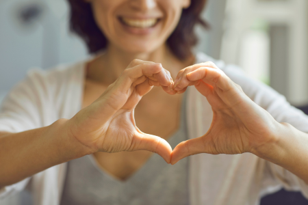A woman making a heart symbol with her hands, representing her gratitude.