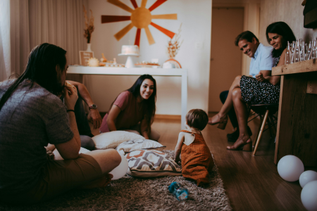 A multi-generational family together in a living room watching a baby play, symbolizing what it is like to live closer to family.