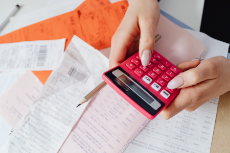 A person with a calculator and receipts, representing someone who is looking to manage debt.