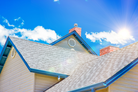 The sun shining on a home, representing the risk of sun and heat damage, something to consider with summer home maintenance.