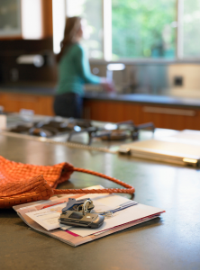 A counter with a purse, keys, and mail that is left to address later in the day.