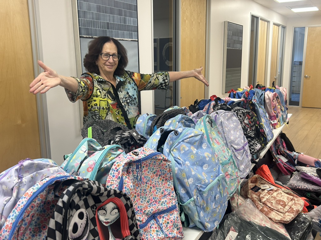 Saresse Zelman of Realty Executives Arizona Territory in front of the backpacks collected in the charity drive.