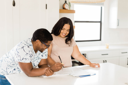 A couple reviewing paperwork while considering the tradeoffs of renting vs buying a home.