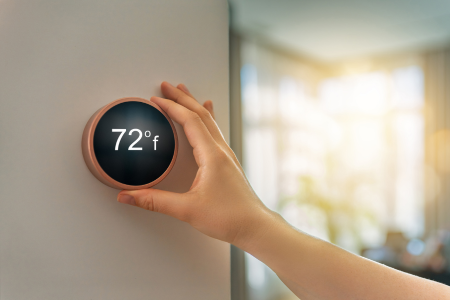 A modern smart thermostat mounted on a wall in a bright hallway- a recommended smart upgrade.