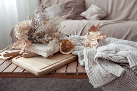 A tabletop with dried botanicals and a chunky knit blanket for fall.