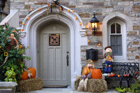 A well-lit front porch decorated for Halloween with a clear walkway and seasonal decor.