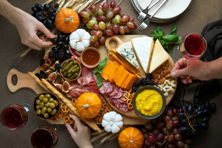 An arranged cheese board with a variety of cheeses, crackers, nuts, olives, and fruit.